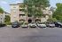Charming apartment exterior with tree-lined entrance and ample parking, offering a perfect blend of modern living and natural beauty.