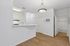 Bright, open-concept kitchen with modern lighting, white cabinetry, and beautiful hardwood floors leading to a pristine bathroom.