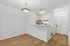 Bright open-concept kitchen with sleek white cabinetry and elegant lighting, complemented by warm wood flooring.