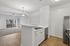 Bright and modern kitchen with sleek white cabinets, stainless steel appliances, and an open view to the inviting living room with fresh flooring and a chic chandelier.
