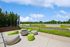 Chic outdoor patio space featuring modern seating and a stylish fire pit, surrounded by lush greenery and bright flower beds.