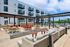 Chic outdoor communal area featuring stylish seating, modern fire pit, and a contemporary apartment backdrop under a bright blue sky.