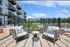 Modern apartment complex featuring private balconies overlooking a beautifully landscaped outdoor pool area with stylish seating.