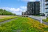 Vibrant rooftop garden with lush greenery and yellow flowers against a backdrop of modern apartment buildings, under a clear blue sky.