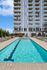 Modern high-rise apartment building with a luxurious poolside area featuring comfortable sun loungers and a sauna room.