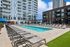 Luxury apartment complex with a sparkling outdoor pool and spacious sun deck, surrounded by modern high-rise buildings with balconies.
