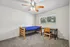 Bright, cozy bedroom with plush carpeting, featuring a modern wooden bed, desk, and chair, accented by natural light from the large window.