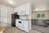 Charming apartment kitchen with modern appliances, black fridge, white cabinetry, and an inviting open-plan living room view.