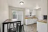 Bright and modern kitchen with white cabinets, sleek countertops, and a cozy breakfast nook with bar stools.