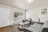 Inviting living room with contemporary grey seating, elegant wood coffee table, and a large window allowing natural light to fill the room.