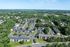 Aerial view of a serene apartment complex surrounded by lush greenery, featuring spacious layouts and ample parking, with a community pool and scenic suburban landscape.