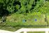Vibrant aerial view of spacious fenced dog park with agility tunnel, enticing natural greenery, and a pathway perfect for pet owners.