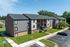 Charming apartment building with modern exterior, surrounded by well-maintained green lawns and convenient parking.