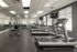 Modern fitness center featuring treadmills, weight machines, and scenic wall art in a spacious, well-lit room.