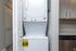 Compact laundry area with modern stacked washer and dryer, adjacent to sleek kitchen cabinetry.