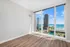 Bright apartment room with elegant wooden flooring, offering breathtaking panoramic views of the city skyline and sparkling blue lake through large floor-to-ceiling windows.
