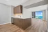 Modern apartment interior featuring sleek wood cabinetry, hardwood floors, and breathtaking floor-to-ceiling windows with stunning ocean views.