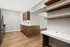 Modern kitchen with sleek wooden cabinetry, stainless steel appliances, and chic open shelving against a stylish, spacious layout.