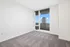 Bright modern apartment room with plush carpeting and floor-to-ceiling windows opening to a balcony with stunning city views.