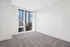 Bright and spacious apartment room with plush carpet flooring and stunning city skyline views through large glass windows.