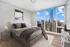 Elegant bedroom with plush bed and prime cityscape views through floor-to-ceiling windows in a modern high-rise apartment.