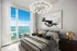 Luxurious bedroom with floor-to-ceiling window offering breathtaking ocean views, modern decor, and elegant lighting.