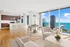 Luxurious open-concept apartment with modern kitchen, inviting dining area, and stunning floor-to-ceiling windows offering breathtaking views of the waterfront skyline.