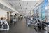 Bright, spacious fitness center with a city view, featuring modern cardio machines, weight equipment, and sleek design.