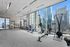 Bright, modern gym with state-of-the-art equipment and expansive city views through floor-to-ceiling windows.