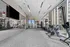 Modern fitness center with large windows, featuring exercise bikes, strength training equipment, punching bag, and floor-to-ceiling mirrors.