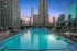 Luxurious rooftop pool with chic chaise lounges against a breathtaking city skyline at sunset.