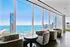 Luxurious apartment lounge with stunning panoramic ocean and city views through floor-to-ceiling windows.