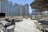 Luxurious rooftop terrace with elegant seating, modern grills, and stunning cityscape views under clear blue skies.