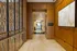 Elegant hallway with sophisticated wood paneling and decorative metal screens, leading to a bright, inviting entrance.