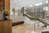 Luxurious apartment lobby showcasing sleek modern design with a grand staircase, elegant seating, and large windows offering city views.