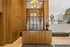 Elegant lobby space featuring warm wood paneling, a stylish decorative screen, and modern lighting, complete with a chic flower arrangement.