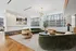 Chic modern living room with luxurious green and tan furniture, elegant lighting, and panoramic city views through large windows.