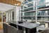 Modern dining area with a sleek wooden table, stylish upholstered chairs, and a large window offering panoramic city views.