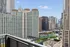 Stunning cityscape view from a modern apartment balcony overlooking high-rise buildings and a serene river.