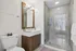 Modern bathroom with sleek finishes, featuring a glass-enclosed shower, elegant vanity with mirror, and bright natural lighting.