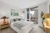 Elegant bedroom with a plush bed, stylish decor, and stunning city views from the balcony.