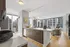Chic urban apartment with open-concept kitchen and living area, featuring floor-to-ceiling windows offering stunning cityscape views.