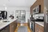Modern kitchen with sleek stainless steel appliances, wood cabinetry, and a chic peninsula counter, overlooking a stylish urban living space.