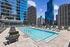 Luxurious rooftop swimming pool surrounded by modern skyscrapers, offering a stunning city view and ample lounge seating for relaxation.