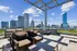 Luxurious rooftop patio with elegant seating and breathtaking city skyline views under a clear blue sky.