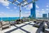 Luxurious rooftop terrace with stylish seating and stunning ocean views, set against a backdrop of modern skyscrapers.