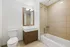 Elegant bathroom with modern fixtures, featuring a sleek vanity with mirror, polished tile bathtub, and pristine toilet, offering a bright and inviting space.