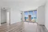 Bright and modern living space with stunning city and lake views through floor-to-ceiling windows, featuring elegant wood flooring.