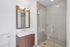 Elegant bathroom with a modern vanity, large mirror, and spacious glass-enclosed shower.