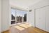 Bright apartment room with floor-to-ceiling windows showcasing stunning cityscape views, accented by sleek wooden floors and modern white walls.